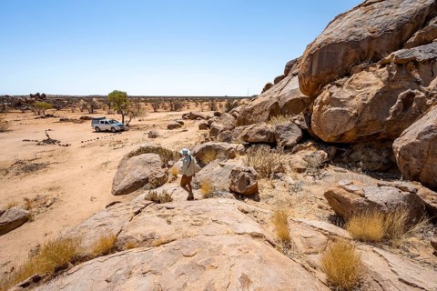 Young man between hills with round smooth rocks, Damaraland, Kunene, Namibia