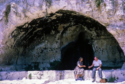 People sitting in rock cut niche at fifth century BC, Greek Theatre at Syracuse, Sicily, Italy,