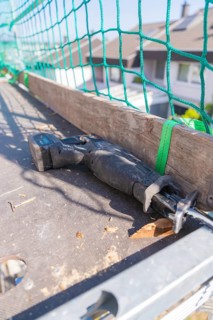 Electric tools on construction site next to green safety net, RABA Solar roof renovation