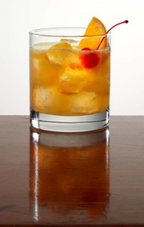 Cocktail on ice throws, cocktail cherry and orange wedge as garnish, studio recording