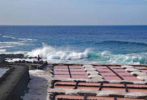 Salt pans at the edge of the sea, with breaking waves in the background under a clear sky, salt