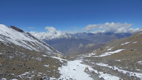 Wide snowy landscape and mountain range with distant views under blue sky, Thorong La, Manang,