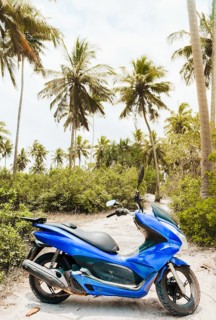 Bright blue typical common motor scooter parked on sandy dirt road. Transportation rentals in asia.