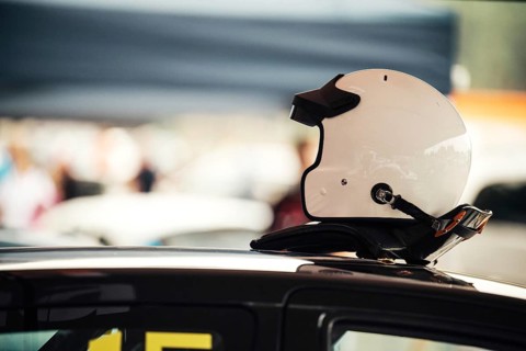 Close-up of a white racing helmet resting on a car's roof. Symbolizing motorsports safety,