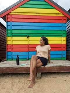 Colorful Brighton Bathing Boxes in Melbourne, Australia, with a person relaxing in front of a