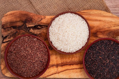 Set of red and black and white rice, in a bowl, on a wooden surface, rustic style, top view