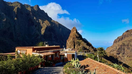 Rustic buildings in a mountain landscape with blooming vegetation under clear skies, Masca,