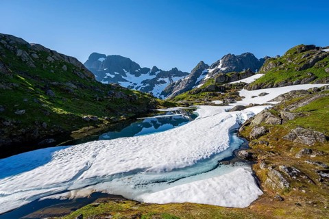 Lake with snow remains, Landscape at the mountain hut Trollfjord Hytta, Rocky mountain peaks with