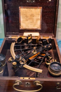An antique sextant in a wooden display case, surrounded by measuring instruments, Bohneberger