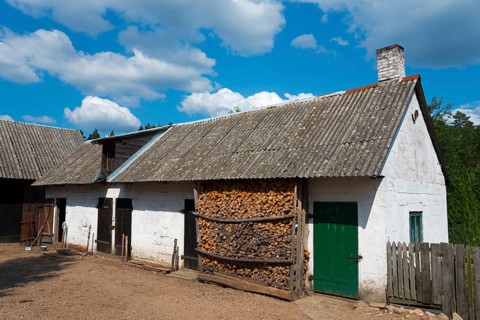 Old rural house with wooden walls and a stacked wood store under a blue sky, farmhouse, Rygol,