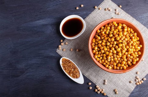 Fried chickpeas with spices in a clay plate on black wooden background, top view, copy space