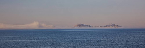 Two islands on the horizon in the morning light with calm sea surface, crossing Rhodes to Symi,