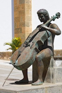 Bronze figure of a cellist Homenaje a la Musica by A. L. Benitez next to the cathedral Iglesia de