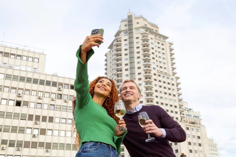 Friends is enjoying a rooftop party, capturing the moment with a selfie They smile and hold glasses