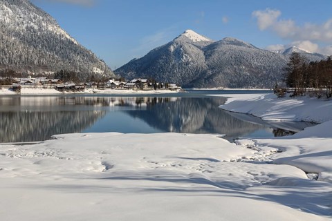 Mountains reflected in lake, village, houses, winter, snow, sunny, Walchensee, behind Jochberg,
