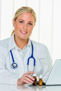 A blonde doctor with a stethoscope prescribing medication, computer, laptop, practice, office