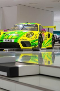 Yellow-green racing car in exhibition with shiny surface and reflection, Porsche Museum, Stuttgart,