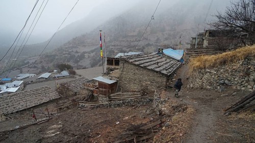 A mountain village on a foggy slope with prayer flags, trekking at Annapurna Circuit, Manang, Nepal