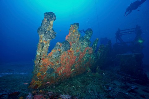A grotesquely shaped wreck rising from the seabed surrounded by blue, dive site Wreck Ville de