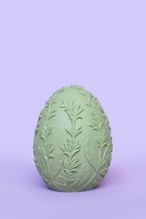 Single green Easter egg with leaf pattern on purple background
