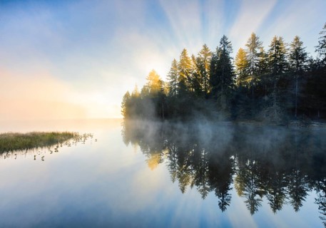 Sunrise over the mirror-smooth mire lake Étang de la Gruère in the canton of Jura, Switzerland