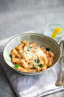 Cavatappi pasta topped with grated parmesan, fresh spinach and spicy tomato sauce, served in a