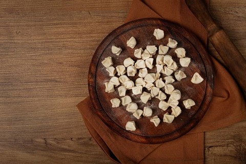 Traditional Turkish dumplings, raw, on a cutting board, top view, no people