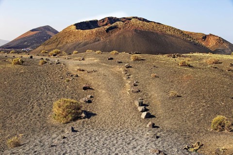 A barren volcanic landscape with dry ground in a lonely atmosphere, El Cuervo Volcano, Lanzarote,