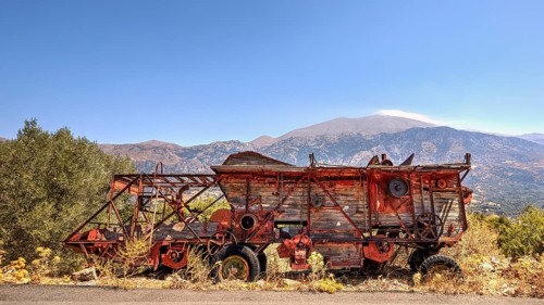 Antique, rusty combine harvester in front of a mountain backdrop under a bright sky, Vehicle wreck,