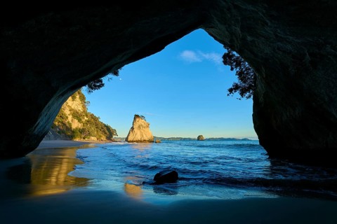 Beach and sea seen from a cave under a bright morning sky, Cathedral Cove, Coromandel, Canterbury,