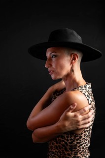 Creative portrait featuring a bald woman wearing a bold, wide-brimmed hat and a leopard print