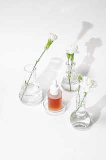 A serene setting of laboratory glassware featuring a skincare serum and fresh flowers, illustrating