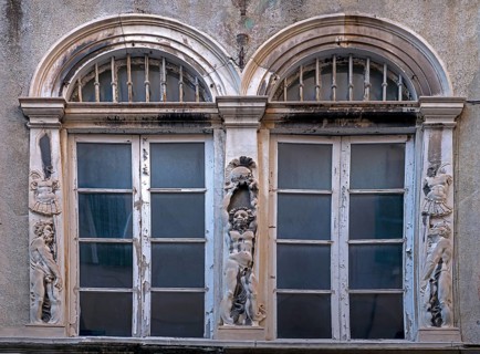 Historic arched windows framed with Roman relief motifs, old town centre in Genoa, Italy