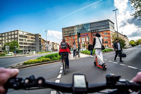 Cycling in the city, inner-city road, cyclist, e-scooter at pavement traffic light, no cycle path,