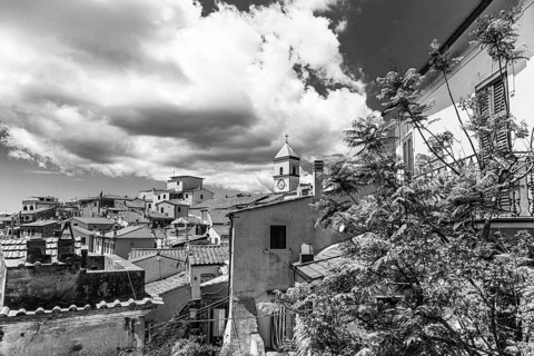 Above the roofs of Capoliveri, behind the church tower of San Michele, black and white photograph,