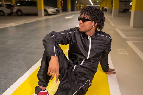Portrait of an african music artist looking away sitting on an urban garage
