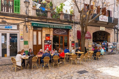 Tourists sit in a cafe in the picturesque mountain village of Valdemossa, Majorca, Balearic