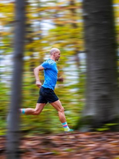 Man in a training session, trail running outdoors, healthy lifestyle, colorful autumn forest,