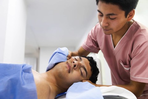 A physiotherapist provides a calming face massage to a patient in an Ecuadorian clinic. The setting