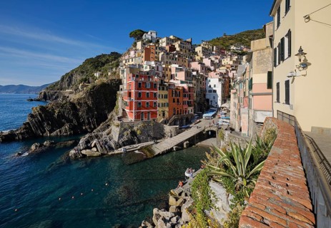 Colourful houses under blue sky, view of the fishing village of Riomaggiore, boats in the harbour,
