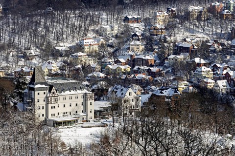 Snowy village with church and snow-covered houses surrounded by wooded hills in a wintry