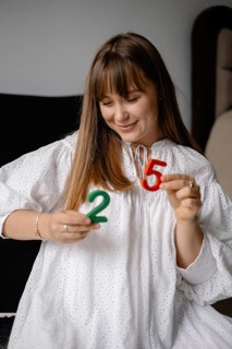 Smiling woman holding green two and red five engaging in playful number learning