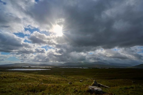 A wide sky and rays of sunshine over an open landscape create a tranquil atmosphere, Rannoch Moor,