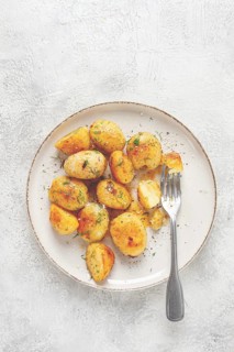Half-eaten fried new potatoes, with butter and dill, on a white plate, with a fork, at home, no