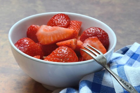 Sliced strawberries in hull with fork, Fragaria