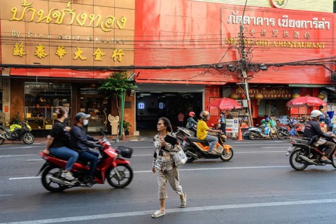 Bangkok, Thailand. February 18th 2025. A local woman crosses Yaowarat road busy with motorcycle