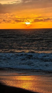 A dramatic sunset over the ocean bathes the sky in warm shades of orange and gold, hiking, Tarrafal