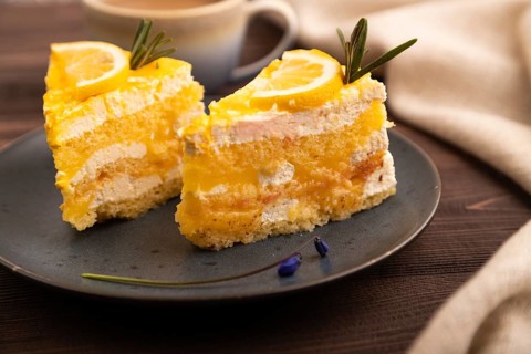 Lemon cake on brown wooden background and linen textile, cup of coffee, side view, close up,