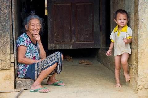 Laotian elderly woman and young boy in a Hmong village in a very simple wooden house, wooden cabin,