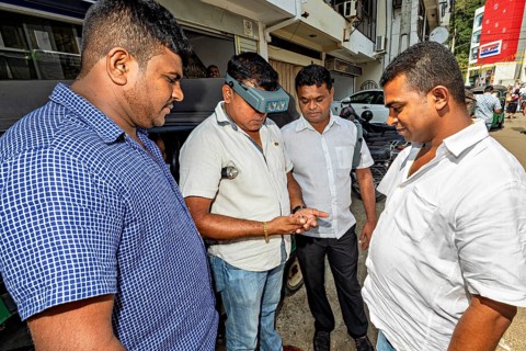 Four men on the street focusing and communicating on a small technical device, the sapphire